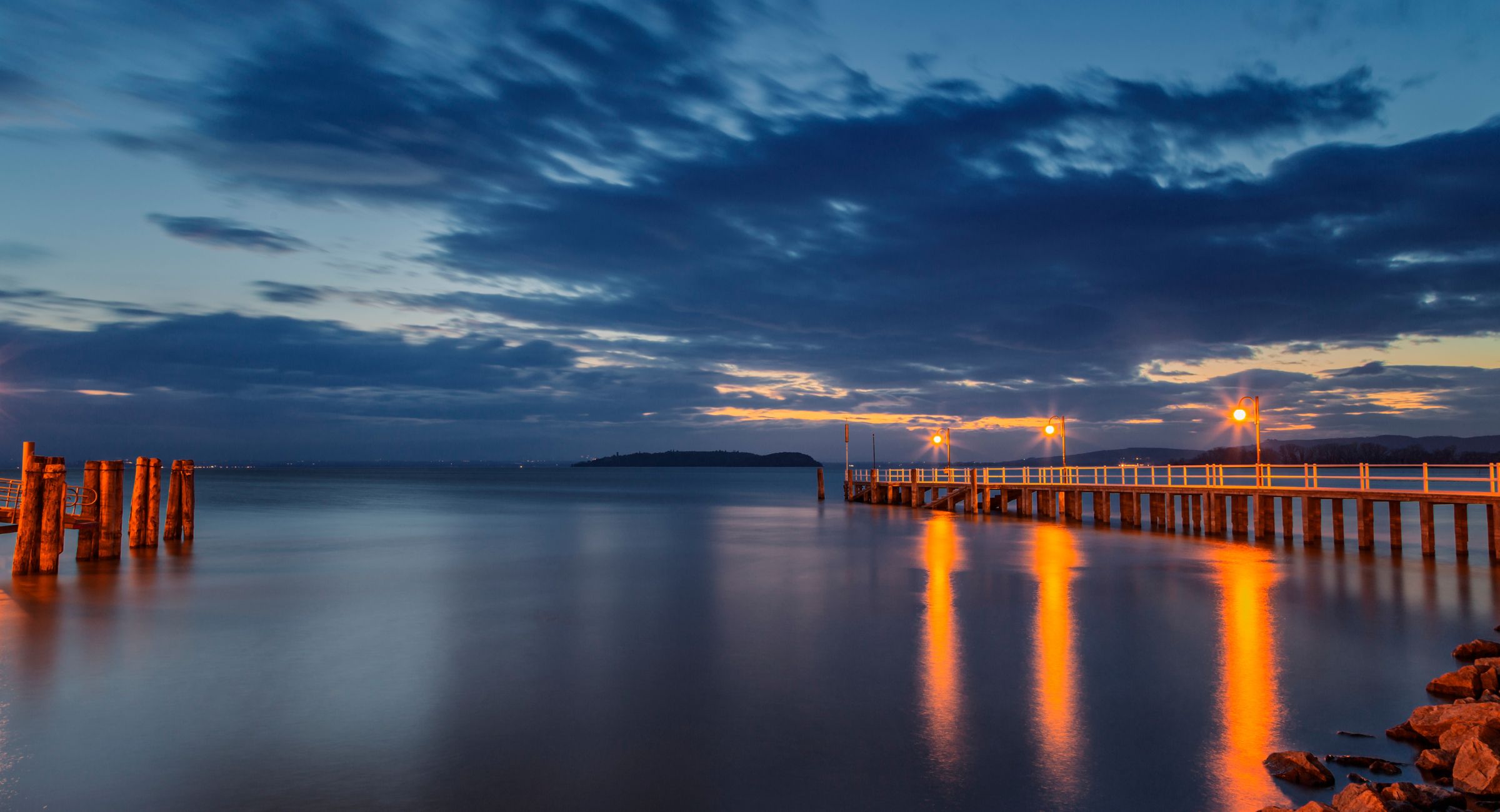 Lake Trasimeno at sunset with a pier reflected in the water